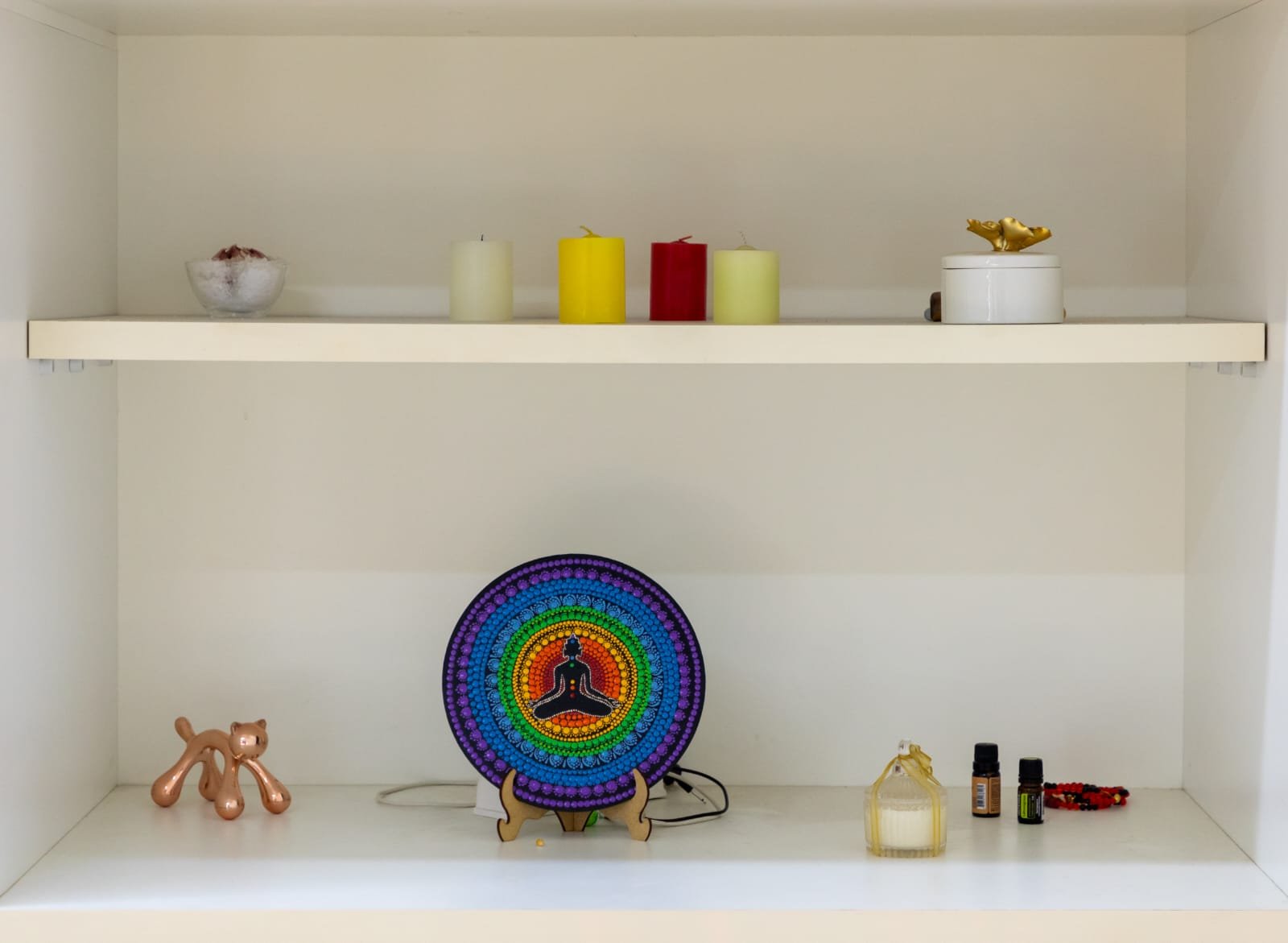 Prateleira com mandala dos chakras e óleos essenciais